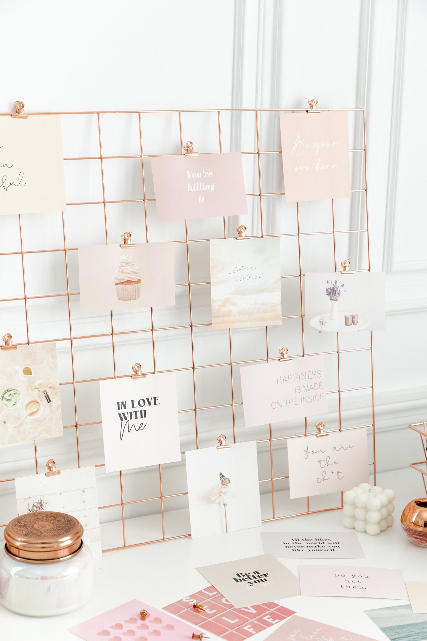 Rose gold bulldog clips styled on a wall grid with vision board cards and desk decor