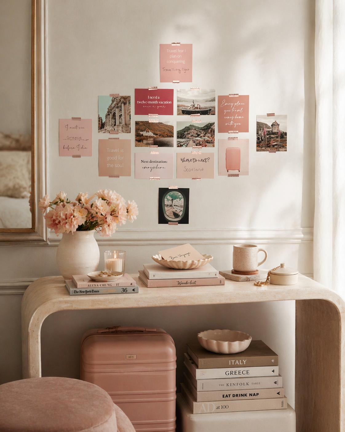 Pastel travel vision board card set arranged above a console table with destination photos, flowers, books and a blush suitcase.