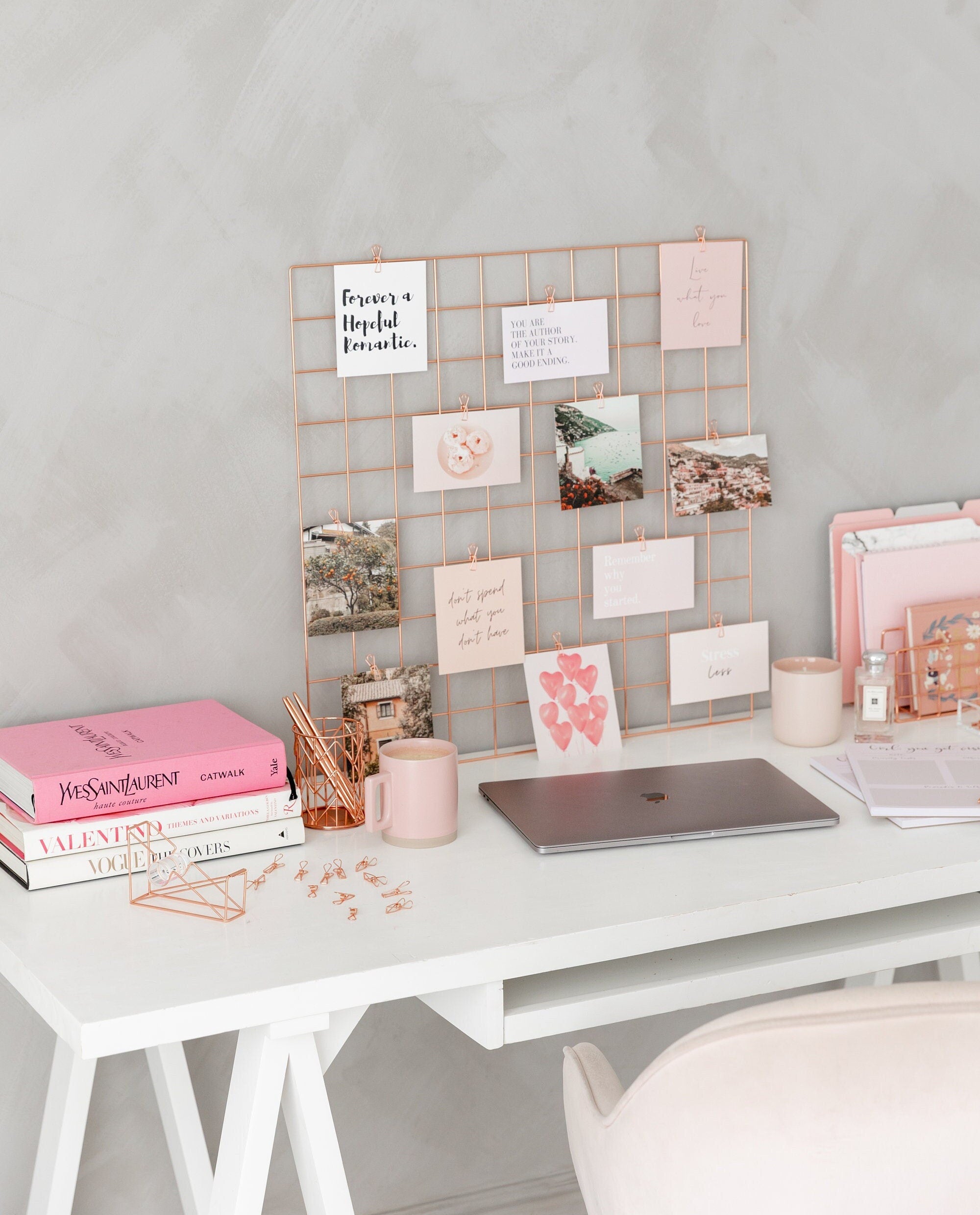 Rose gold vision board displayed in a workspace with laptop, books and pink desk accessories