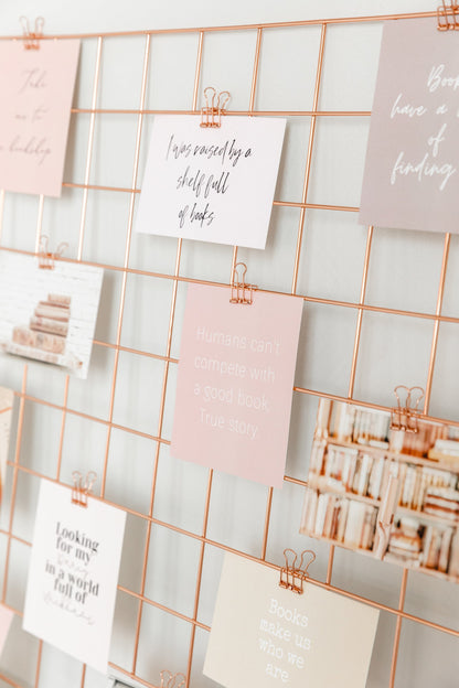 Bookish cards clipped to a rose gold wall grid for a reading-inspired vision board