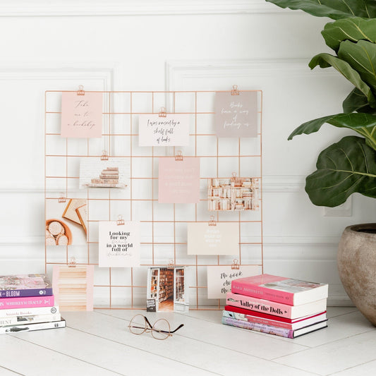 Bookish vision board cards displayed on a rose gold wall grid with books and clips