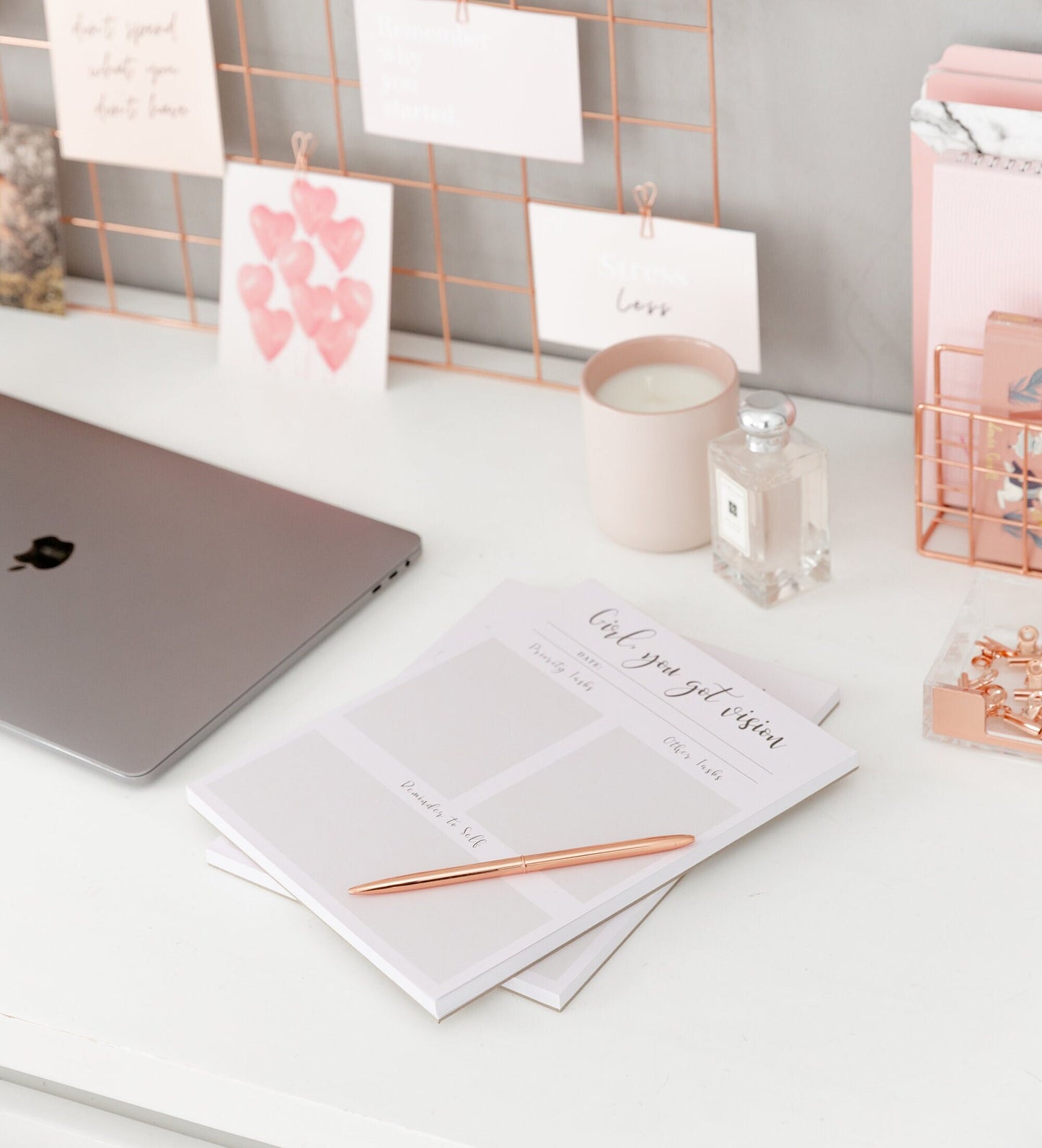 Daily planner notepad styled with pink stationery cards and desk accessories