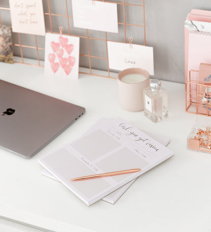 Daily planner notepad styled with pink stationery cards and desk accessories