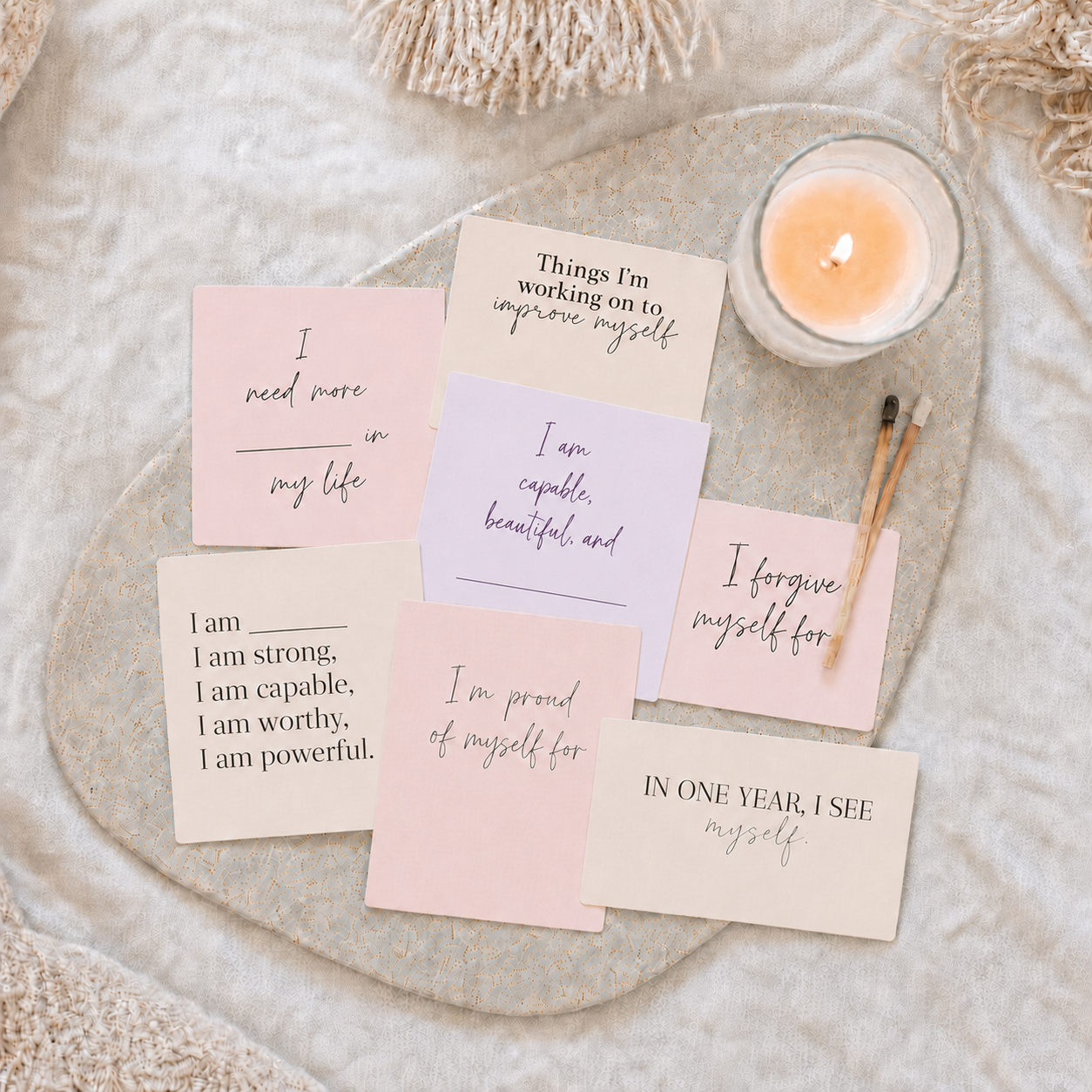 Goal-setting vision board cards arranged in a cozy self-care flat lay with a candle, neutral tray, and soft blush-toned cards