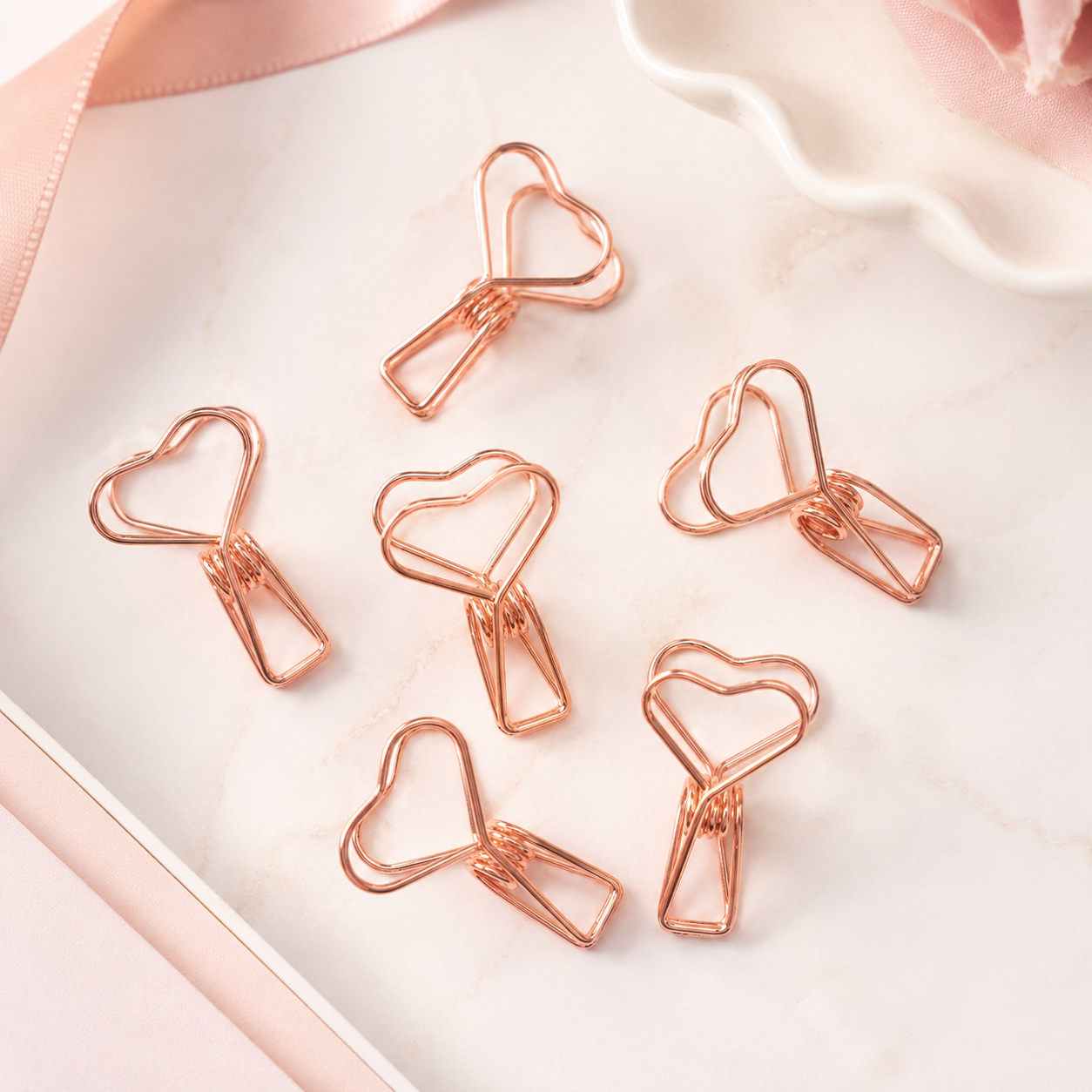 Six rose gold heart clips on marble surface with pink ribbon