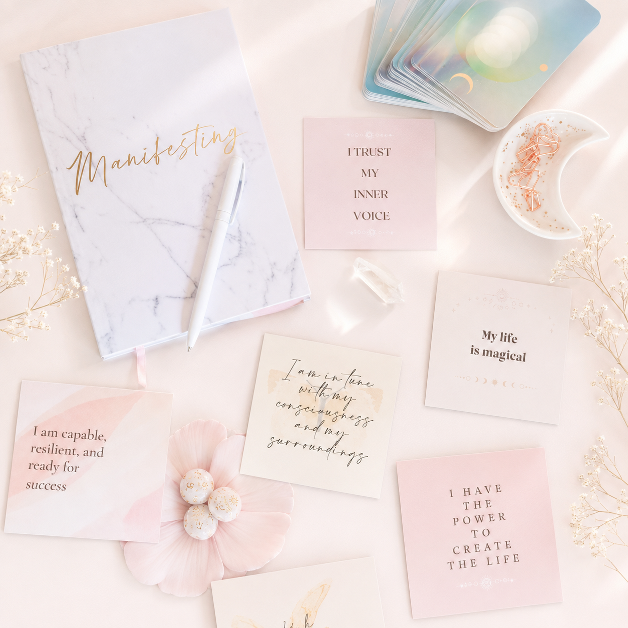 Pastel affirmation cards arranged with a marble journal, oracle cards, crystal and rose-gold clips.