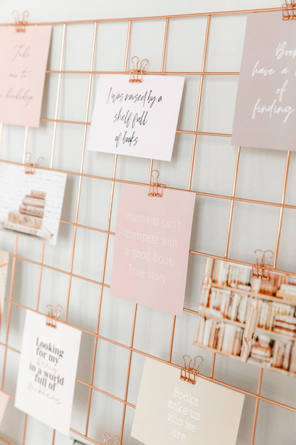 Rose gold binder clips holding cards on a wall grid