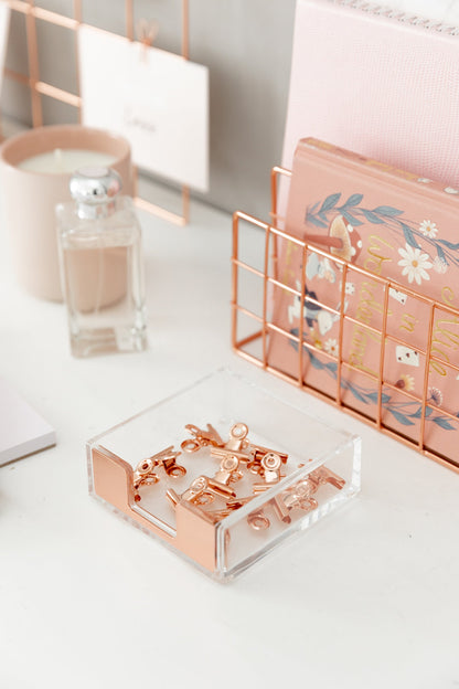 Rose gold bulldog clips styled with a desk organizer, candle, and stationery