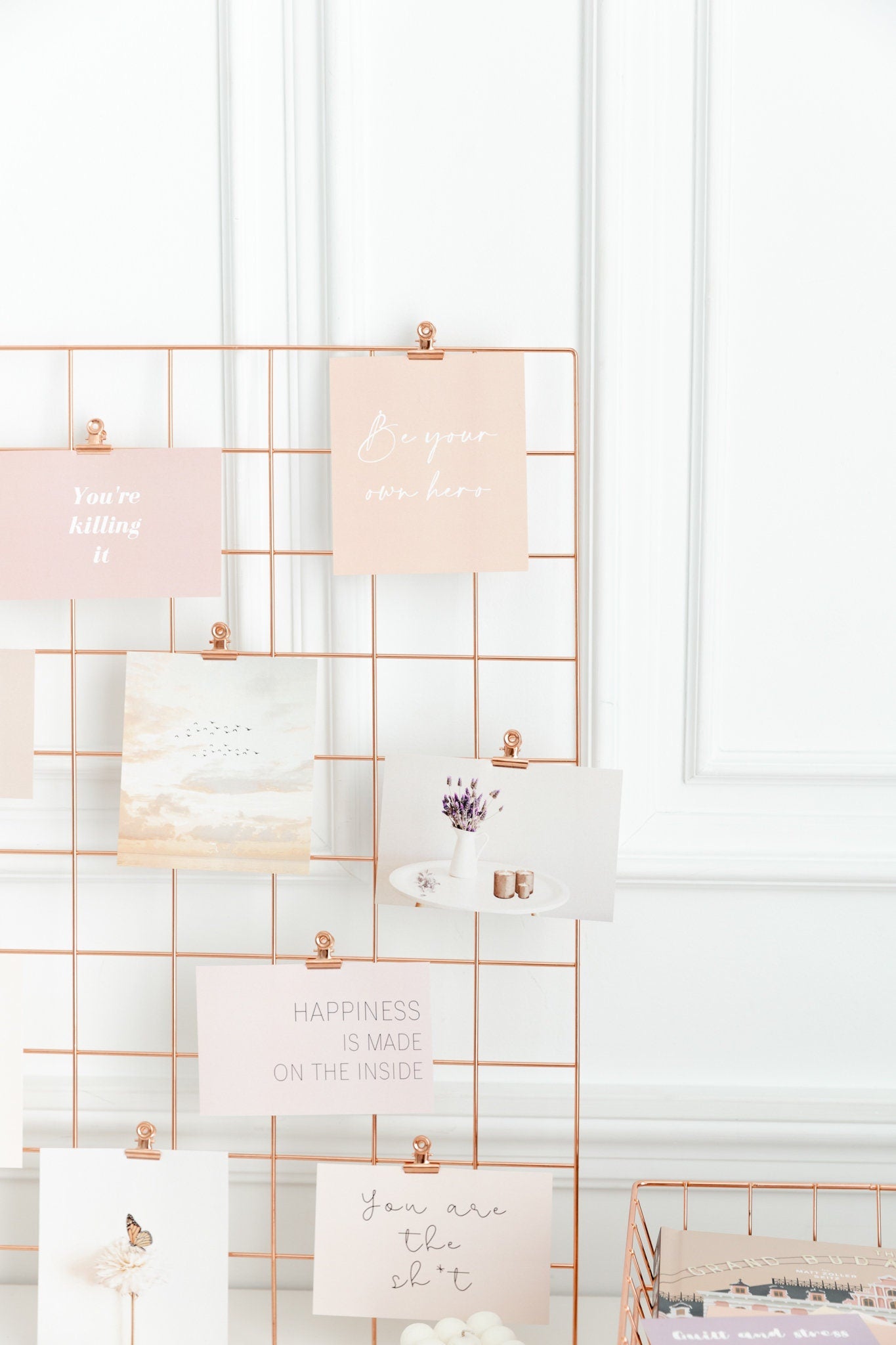 Rose gold bulldog clips holding cards on a clean wall grid display