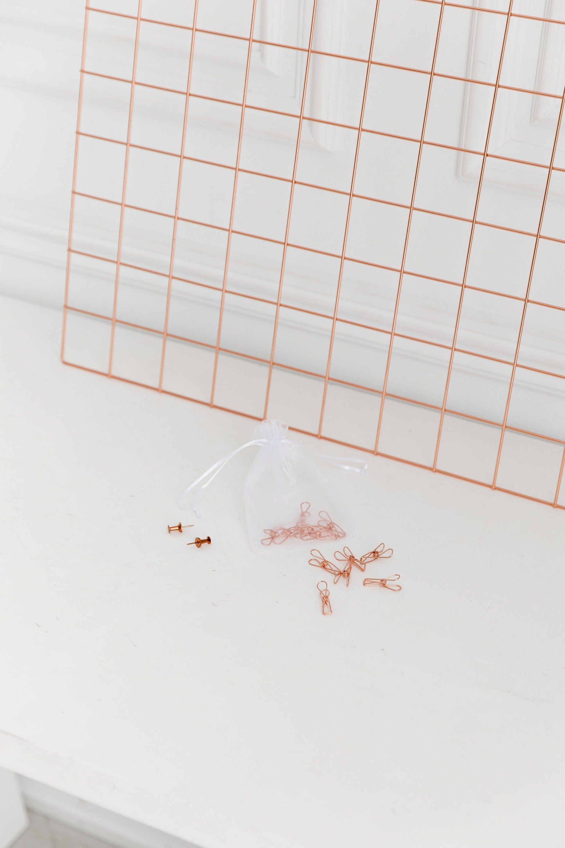 Side view of a rose gold wall grid hanging on a white wall