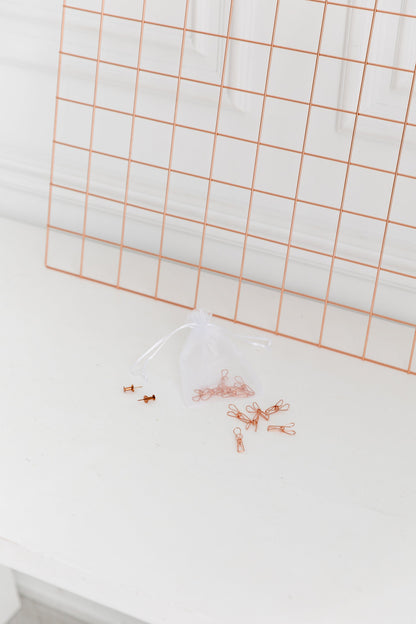 Side view of a rose gold wall grid hanging on a white wall