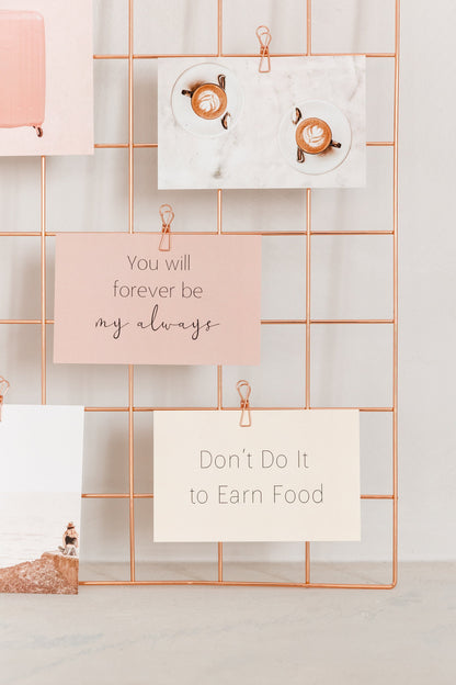 Rose gold wire clips holding cards on a wall grid display