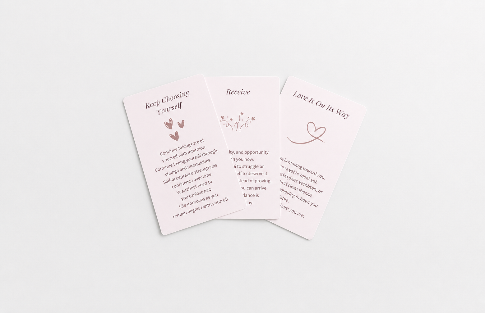 Three pastel oracle cards featuring messages about self-worth, receiving support and love, arranged on a soft white background