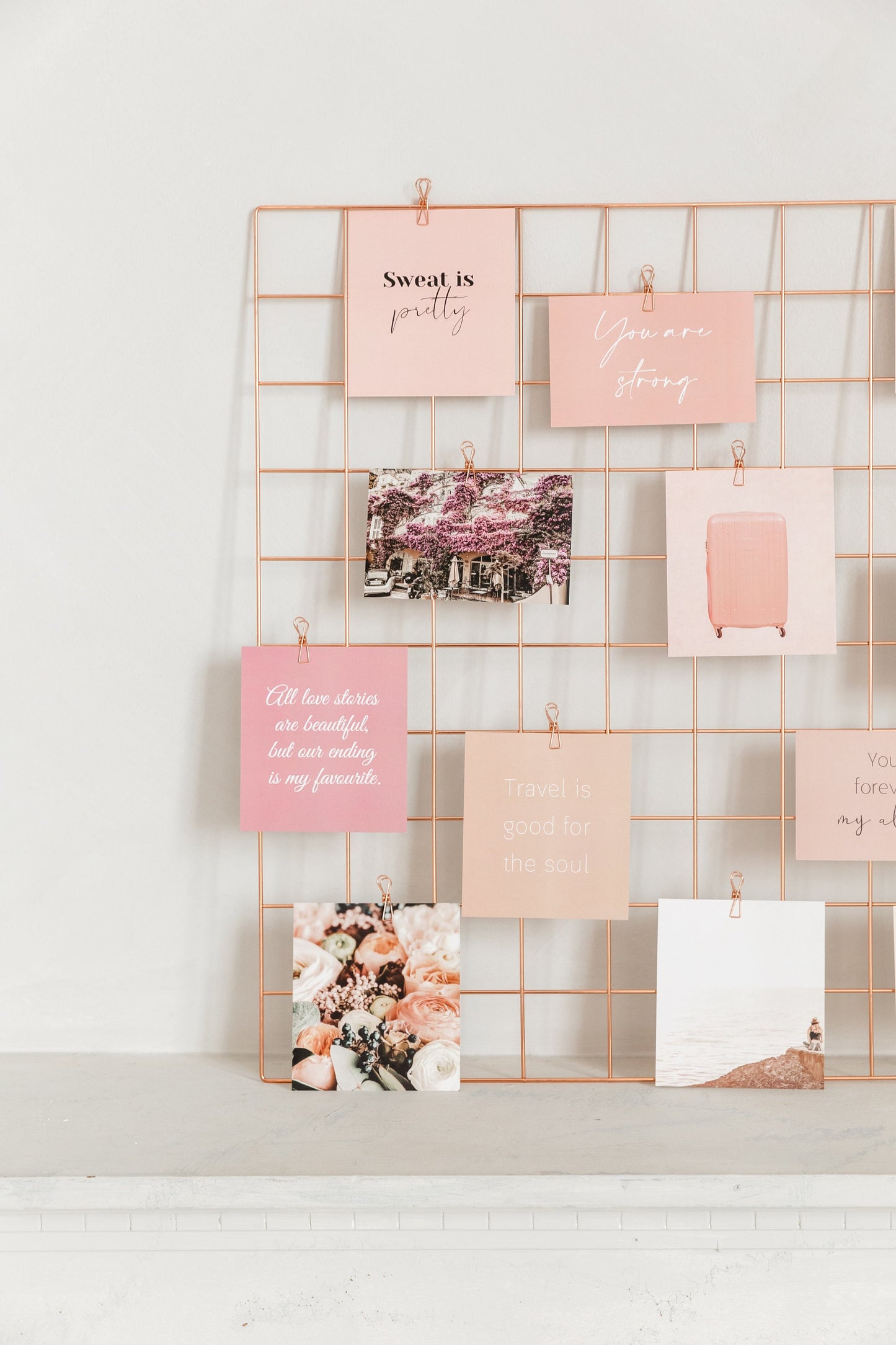 Travel vision board cards clipped to a rose gold wall grid